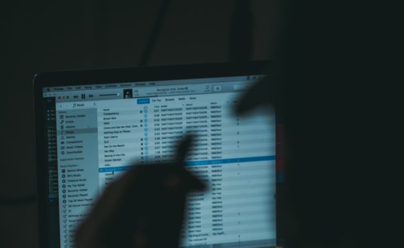 silhouette photography of man facing opened MacBook Pro with iTunes display