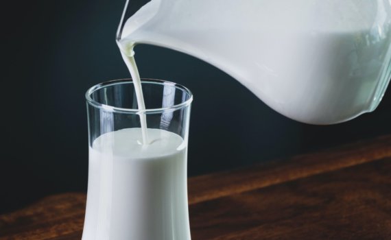 person pours milk into glass