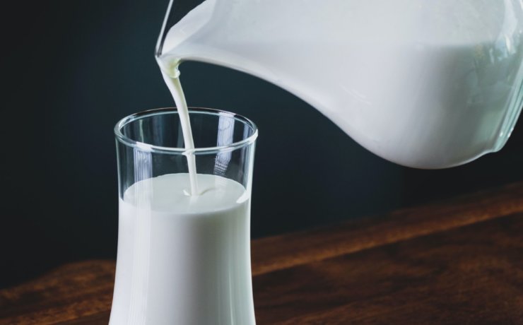 person pours milk into glass
