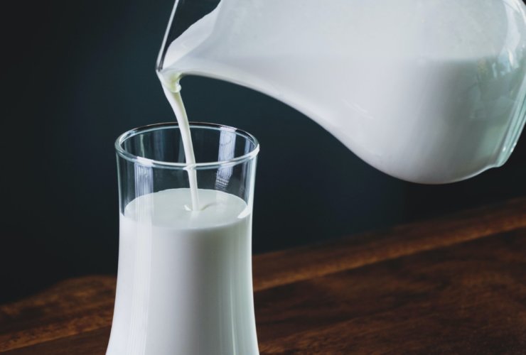 person pours milk into glass