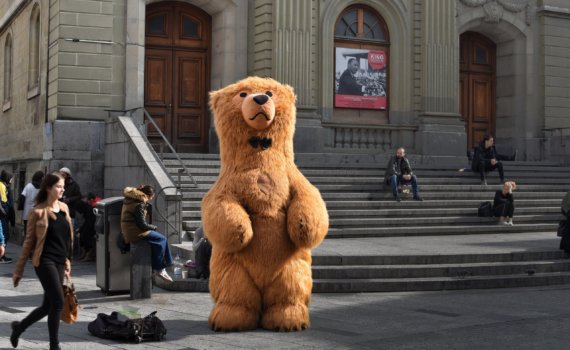 brown bear mascot standing in front of building