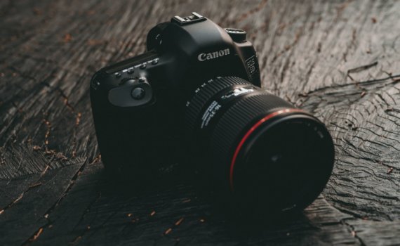 black Canon EOS DSLR camera on brown wooden board