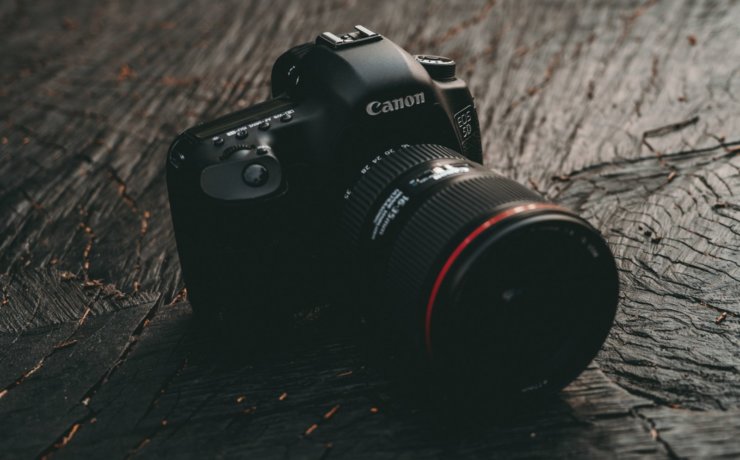 black Canon EOS DSLR camera on brown wooden board