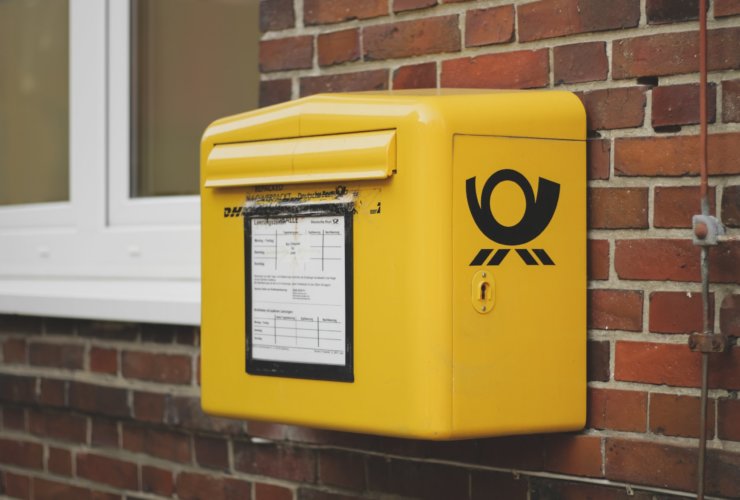yellow mailbox on brown wall bricks