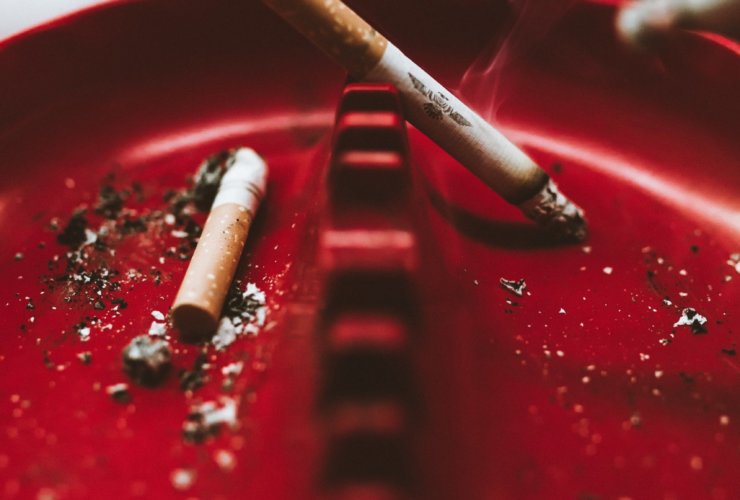 shallow focus photo of white cigarette stick on red ashtray