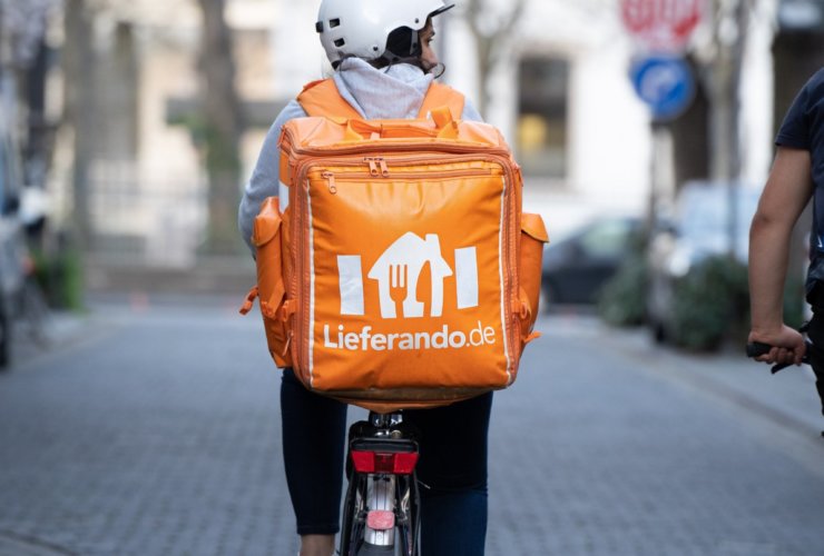 man in orange backpack riding on motorcycle on road during daytime