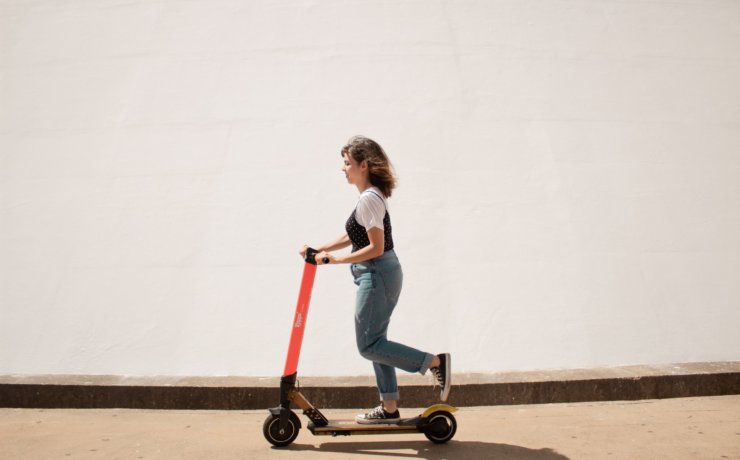 woman in white shirt and blue denim jeans riding red and black kick scooter